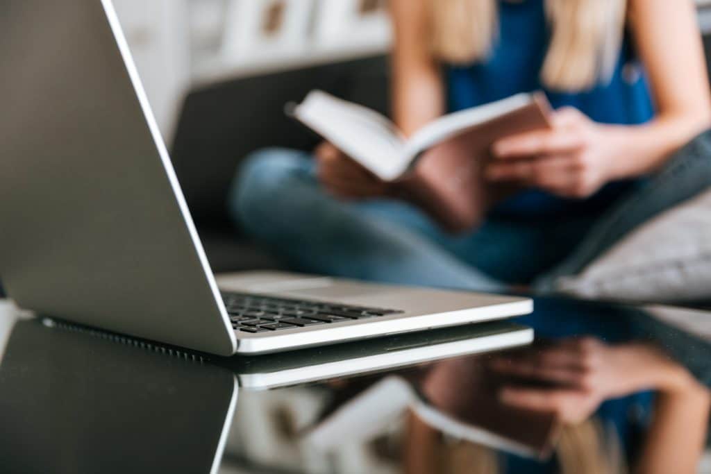 laptop table near woman reading book home