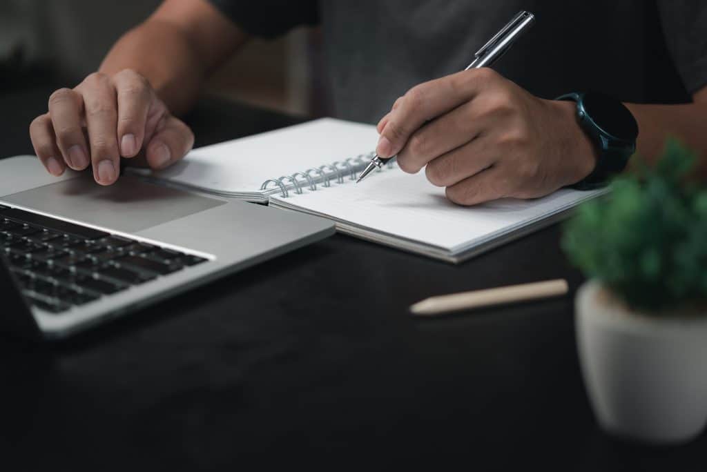 man hands with pen writing notebook officelearning education workwrites goals plans make wish list desk